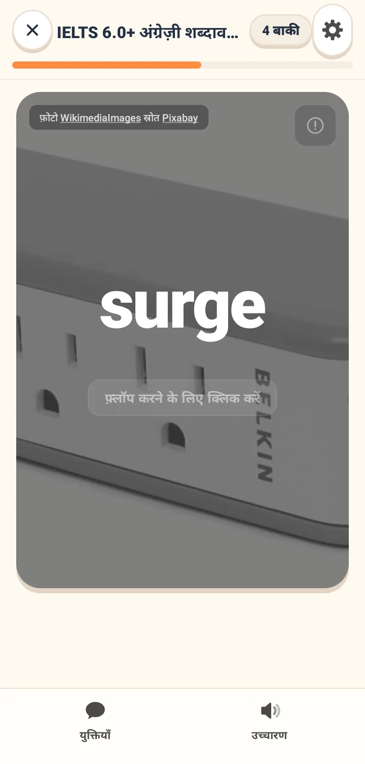 फ्लैशकार्ड के सामने का हिस्सा, जिसके बैकग्राउंड में एक फोटो है और बीच में अंग्रेज़ी का एक बड़ा शब्द है। नीचे टैप करके पलटने का इशारा है, और सबसे ऊपर प्लान का नाम और बचे हुए कार्ड की संख्या है।