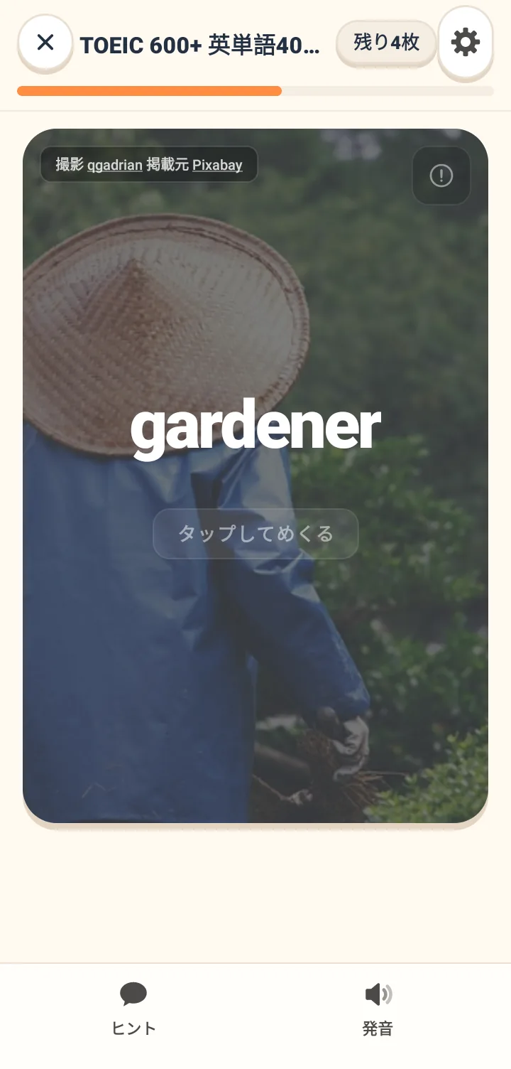 単語カードの表面。背景にシチュエーション写真があり、中央に大きく英単語、下部にタップして裏返すヒント、上部にプラン名と残りの枚数が表示されている。